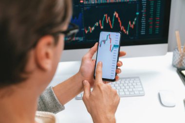 Akıllı borsa yatırımcıları ekranda akıllı telefon ile piyasa borsasını işaret ederek dizüstü bilgisayarın yanı sıra en yüksek dinamik yatırım oranını göstererek, modern işyerindeki veri planlamasına odaklanıyorlar. Bireysel.