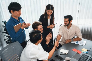 Çeşitli ofis çalışanları stratejik iş pazarlama toplantısı üzerine anlaşma yaptıktan sonra el sıkışıyor. Takım çalışması ve olumlu tutum verimli ve destekleyici bir iş yeri yaratır. Tedbirli