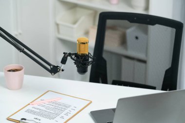 Beyaz masada duran tüm canlı yayın setleri dizüstü bilgisayar, mikrofon, kulaklık, ağaç, senaryo notu ve kalemden oluşur. Sosyal medyada canlı yayında sunucu kanalı için beklemedeyiz. Taktik.