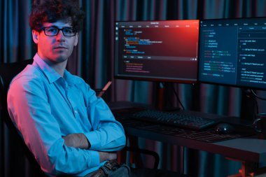 Uygulama ekranı arkaplanındaki kodlama programında gece vakti çevrimiçi yazılım geliştirme bilgisiyle kameraya bakan IT geliştiricisi güncellenmiş yazılım donanımı yaratıyor. Toplayıcı.