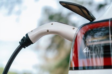 Kapalı EV şarj kolu fişe takıldı veya elektrikli arabaya bağlandı, EV araba aküsünü temiz çevre için sıfır CO2 emisyonu ile alternatif ve sürdürülebilir enerjiyle şarj etti. Kalıcı