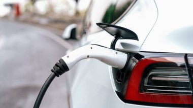 Panorama kapatma EV şarj kolu fişe takıldı veya elektrikli arabaya bağlandı, temiz çevre için sıfır CO2 emisyonu ile alternatif ve sürdürülebilir enerjiyle EV araba aküsünü şarj etti. Kalıcı