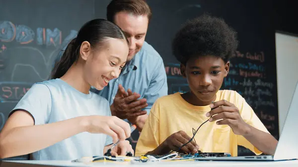 Caucasian Teacher Talking Electric Tool While Student Fixing Robotic Model — Stock Photo, Image
