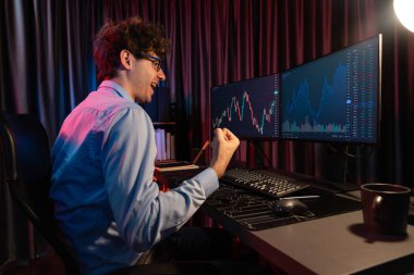 Başarılı genç tüccar, küresel piyasadaki en yüksek kar getiren online veri grafiğini gerçek zamanlı olarak neon ışıklı modern ofiste yükselterek değerli hisse senedi yatırımları elde etti. Toplayıcı.