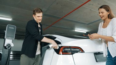 Elektrikli araba sürücüsü, arabadaki uygulama ekranında şarj durumu, menzil ve şarj limitini kontrol ediyor. Akıllı teknoloji aygıtı, EV arabasının araba aküsündeki elektrik depolama verilerini şarj ettiğini gösteriyor..