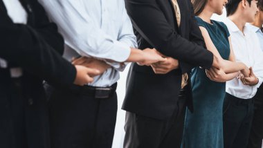 Mutlu ve gülümseyen çok ırklı ofis çalışanı, sinerjiyi ve ticari başarı için işbirliğini destekleyen bir kuyrukta el ele tutuşuyor. Modern işyerinde çeşitli profesyonel ofis çalışanları arasında bağ var. Uyum