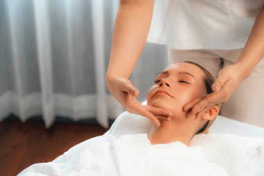 Kafkasyalı kadın stres önleyici kafa masajından ve lüks tatil beldesi ya da otel spa salonundaki modern ışık ortamında yüz güzelliği eğlencelerini şımartmaktan hoşlanıyor. Sessiz.