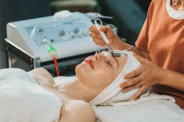 Güzel genç kadınlar profesyonel doktordan yüz masajı alırken spa yatağında yatarlar. Cildi elektrikli yüz makinesiyle çevrili çekici bir kadın. Huzur.