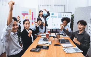 İş adamları TV ekranında başarılı bir sunum veya veri analizi toplantısından sonra kutlama yapıyorlar. Mutlu takım ofis odasında toplanıyor, kutlama jestleriyle işbirliği için tezahürat yapıyorlar. Uyum