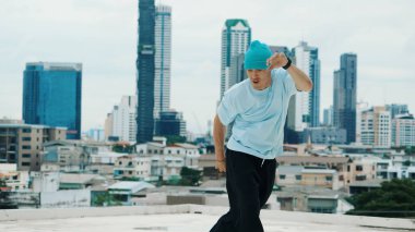 Beyaz dansçı çocuk şehir veya şehirle çatıda sokak dansı yapıyor. Genç adamın sokak dansı yaparken dondurucu poz vermesi. Break dans. Açık hava sporu 2024. ÇalışmaComment.