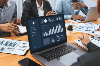 Çok ırklı analist ekibi toplantı masasındaki finansal verileri analiz etmek için BI Fintech yazılımı kullanıyor. Finansal konsol veri ekranında pazarlama göstergesi için analiz edilmiş grafikle birlikte. Uyum