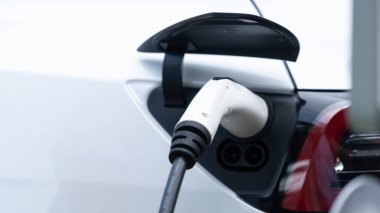Elektrikli araç portuna bağlı EV şarj prizi kolu şarj istasyonundan şarj oluyor. Modern tasarlanmış EV araba ve daha iyi bir gelecek için temiz enerji sürdürülebilirliği. Panorama Senkronları