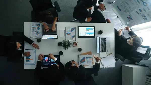 Top down view of manager project pointing at whiteboard with mind map and financial graph and explain marketing idea while diverse investors listening and analyze stock investment chart. Directorate.