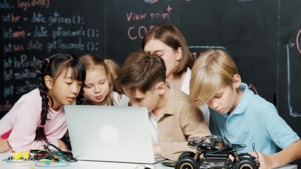 ラップトッププログラミングエンジニアリングコードとライティングプログラムを使用しているコーカサス人の少年は 若い白人教師がブラックボードのStemテクノロジークラスルームでコントローラを保持し 迅速に書かれています エラー — ストック動画