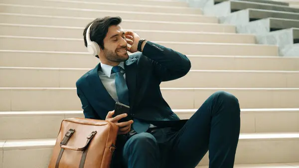 Smart business man listening and enjoy music while wear headphone. Profession project manager smiling while getting good news, getting promotion, increasing sales. Relaxing man enjoy music. Exultant.