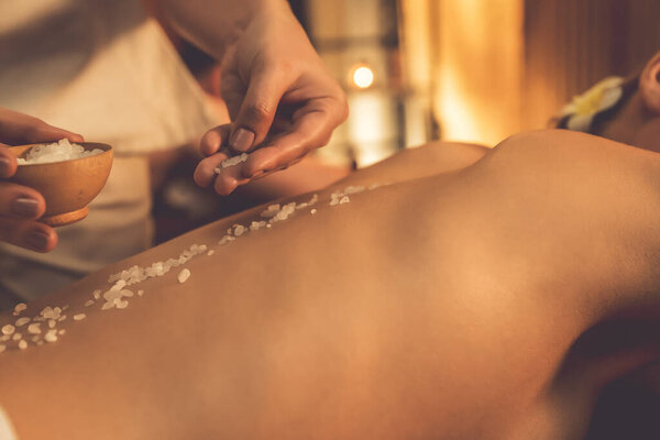Крупным планом пару клиентов, имеющих пилинг лечение в роскошном спа-салоне с теплой свечи окружающей среды. Косметическое лечение бальзамическим скрабом в Health spa scrub. Quiescent