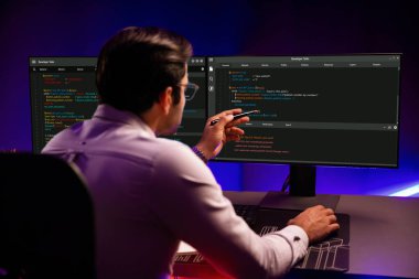 İki pc ekranda veri yazılım geliştirme üzerine çalışan akıllı bilişim geliştiricisi, neon ışıklı siber ofiste güncellenmiş uygulama programı güncellenmiş web sitesi sayfası sistemi yaratıyor. Tahmin et..