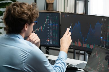 Piyasa stoku grafiği üzerinde çalışan genç profesyonel tüccar ev ofisindeki gerçek zamanlı ekranlara yatırım yaparak önemli döviz kuru kavramları yazarak analiz ediyor. Toplayıcı.