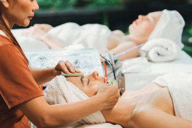 Güzel genç kadınlar profesyonel doktordan yüz masajı alırken spa yatağında yatarlar. Cildi elektrikli yüz makinesiyle çevrili çekici bir kadın. Huzur.