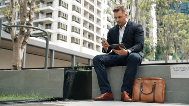 Kafkas iş adamları yeşil şehirde otururken tablet üzerinde çalışıyorlar. Uzman yönetici iş ekibiyle çalışırken finansal veri analizi yapmak ve aramak için tablet kullanıyor. Urbane.