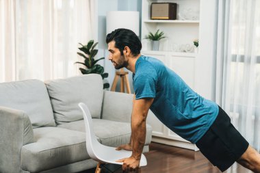 Atletik vücut ve aktif sporcu, sağlıklı vücut çalışma yaşam tarzı konsepti olarak neşeli ev egzersizlerinde kas kazanma egzersizi yapmak için mobilyaları kullanıyor..