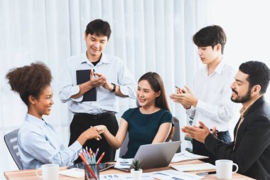 Çeşitli iş arkadaşları başarıyı şirket işyerindeki el sıkışma ve takım çalışmasıyla kutluyor. Çok kültürlü, mutlu profesyonellerden oluşan bir ekip ofiste tokalaşarak birlik oldular. Uyum