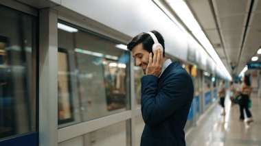 Proje yöneticisi tren istasyonunda şarkı seçmek için cep telefonu tutarken kulaklık takıyor. Zeki iş adamı bulanık bir geçmişi olan treni beklerken rahatlatıcı müzik dinliyor. Sevinçli..