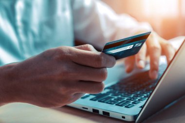 Genç adam, laptop bilgisayar başvurusu ya da web sitesinde online alışveriş yapmak için kredi kartı kullanıyor. E-ticaret ve online alışveriş konsepti. uds