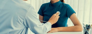 Hasta klinikte ya da hastane ofisinde doktor randevusuna gidiyor. Hastaların nabzını steteskopla kontrol ederken, doktor semptomları muayene ediyor ve teşhis ediyor. Panorama Katı