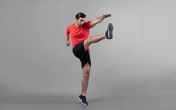 Full body length gaiety shot athletic and sporty young man with fitness in cardio exercise, kicking position posture on isolated background. Healthy active and body care lifestyle.