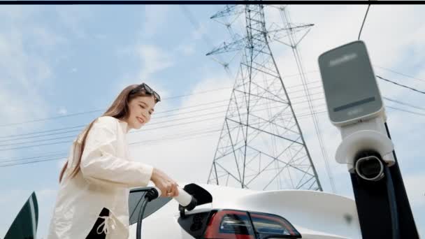 底部视图慢动作妇女充电电动汽车电池充电站连接电网塔电力工业设施作为环保汽车的电力工业 — 图库视频影像