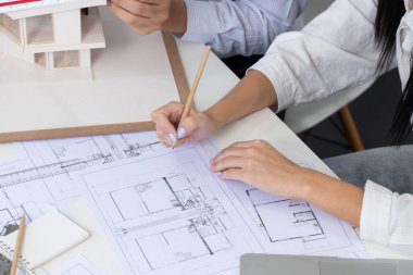 Profesyonel erkek mühendis ev modelini cetvel kullanarak ölçerken güzel bir iş arkadaşı da plan üzerinde yazarak birlikte çalışıyor. Yaratıcı tasarım ve takım çalışması. - Yakın çekim. Tertemiz..