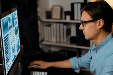 Akıllı iş adamı iş paragrafı dinamik pazarlama analizi planını analiz ediyor. Kağıt kağıtları ve bilgisayar monitörü raporlarını gece evdeki belge verileriyle karşılaştırmak için hazırlıyor. Bireysel.