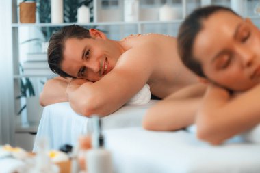 Lüks spa salonlarında sıcak mum ışığında cilt bakımı gören mutlu çift müşterisi. Sağlık kaplıcasında güzellik tedavisiyle tuz temizliği. Sessiz.