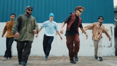 Bir grup hip hop koreografı duvarda sokak dansı yapıyor. Genç yakışıklı dansçı takımı break dans çalışıyor, modern ritme ayak uyduruyor, canlılık hissi veriyor. Açık hava sporu 2024 hiphop..