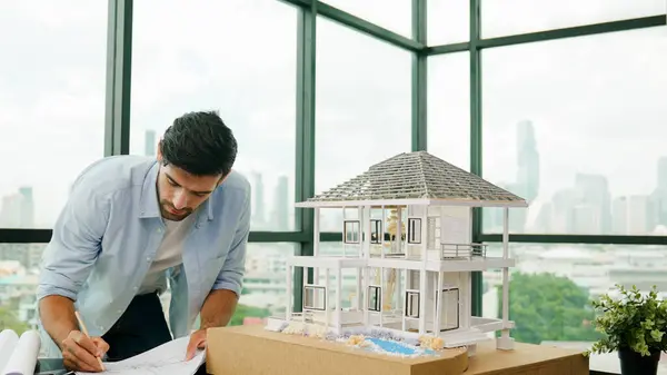 Professional architect engineer taking a note in blueprint house model. Businessman decide to invested money in real estate project. Project manager checks house by comparing with plan. Tracery