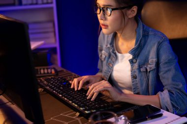 Genç, Asyalı yaratıcı bir kadının satış hedefi raporundan elde ettiği karı analiz etmesi, e-posta ile iş piyasası raporlarını karşılaştırması, gece neon ışığı altında not defterine not yazması. Taktik.