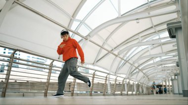 Profesyonel hippi kulaklık takıyor ve hip hop müzik dinleyip hip hop dansı yapıyor. Çekici, yakışıklı break dansçı dondurucu poz veriyor. Sokak dansı. Açık hava sporu 2024. Yumuşak bir şekilde..