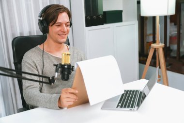 Akıllı yayıncının sunucu kanalı canlı sosyal medya yayını ile dinleyicilere senaryo okuyarak, kulaklık takarak modern ev stüdyosundaki video flamalarını kaydediyor. Bireysel.