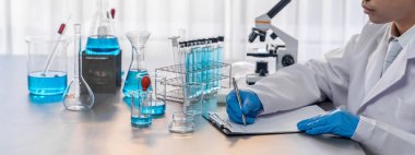 Aşı ilacı ya da antibiyotik için tıbbi laboratuvarda kimyasal deney yaptıktan sonra elde kaydedilen veriler yakından inceleniyor. Bilimsel kimya laboratuvarı ve tıp araştırma konsepti. Neoterik