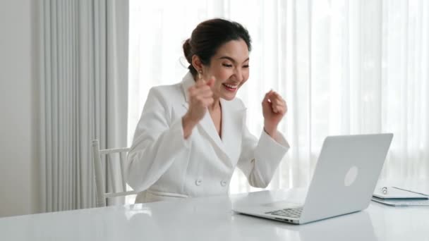 若いアジアのビジネスマンは 大きなセールスや成功したビジネスキャンペーンを祝います ラップトップと彼女の机の上に座っている間 優れた笑顔と興奮した表情 ヴァンシー オフィス ワーカー — ストック動画