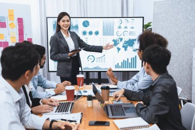 Genç Asyalı iş kadını modern toplantıda TV ekranında veri analizi paneli sunuyor. Bir grup iş adamıyla konferans odasında iş sunumu. Uyum