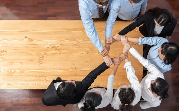 Multicultural business people holding hand together in circle. Unity teamwork in office business workplace. Diverse ethnic office worker engaged in team building. Panorama top view. Meticulous