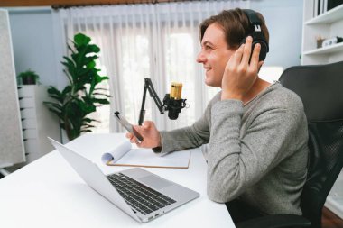 Sunucu kanalı, gülümseyen akıllı yayıncı kaydı, senaryosu ve akıllı telefonuyla sosyal medyada sohbet programı, kulaklık takarak modern ev stüdyosundaki video flamalarını kaydediyor. Bireysel.