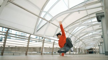 Hipster 'ın kulaklık taktığı ve enerjik adımlar atarken hip hop dinlediği bir sahne. Break dansçı dondurucu poz veriyor. Sokak dansı. Modern yaşam tarzı. Açık hava sporu 2024. Yumuşak bir şekilde..