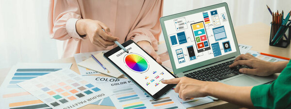Cropped image of interior designer team presents color by using color palette while laptop displayed UI and UX designs for mobiles app and website. Creative design and business concept. Variegated.