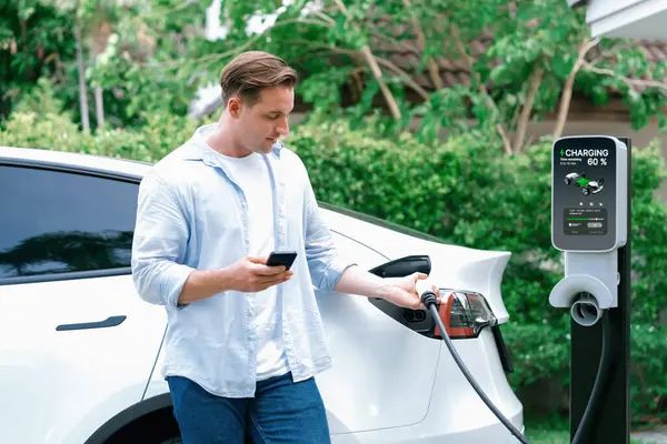 现代环保男子充电电动车从家庭电动车充电站 创新的电动汽车技术用于跟踪能源使用情况 以优化国内的电池充电 同步操作 — 图库照片