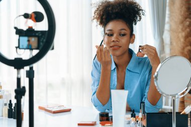 Kadın nüfuzlu kişi canlı yayında video görüntülerini çekiyor. Makyaj çok önemli sosyal medya ya da blog. Kozmetik stüdyosu ışıklandırmalı mutlu genç kız çevrimiçi pazarlama oturumu yayını için..