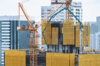 Dış gökdelenlerin, kule vinçleri olan inşaat alanının görüntüsü. İnşaat halindeki şehir manzarası. Binanın tadilatı için çalışan vinçler var. Mavi gökyüzü arka planı. Mimari. Süslü.