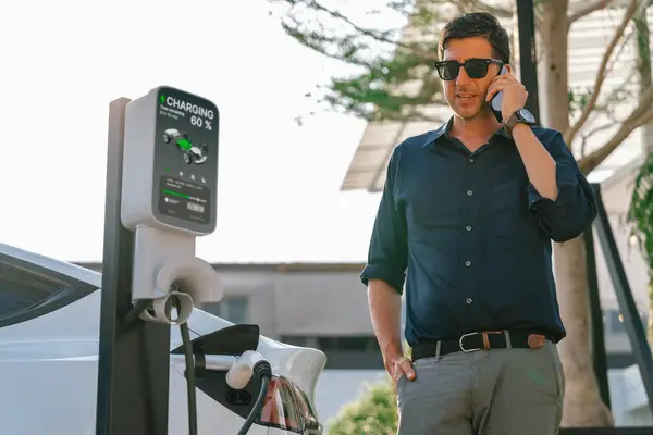 Genç Adam Telefonda Konuşurken Yeşil Şehir Parkındaki Elektrikli Aracı Şarj — Stok fotoğraf